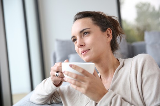 Peaceful woman relaxing at home with cup of tea