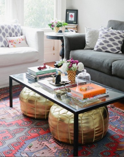 two-gold-poufs-under-a-glass-coffee-table-in-a-living-room
