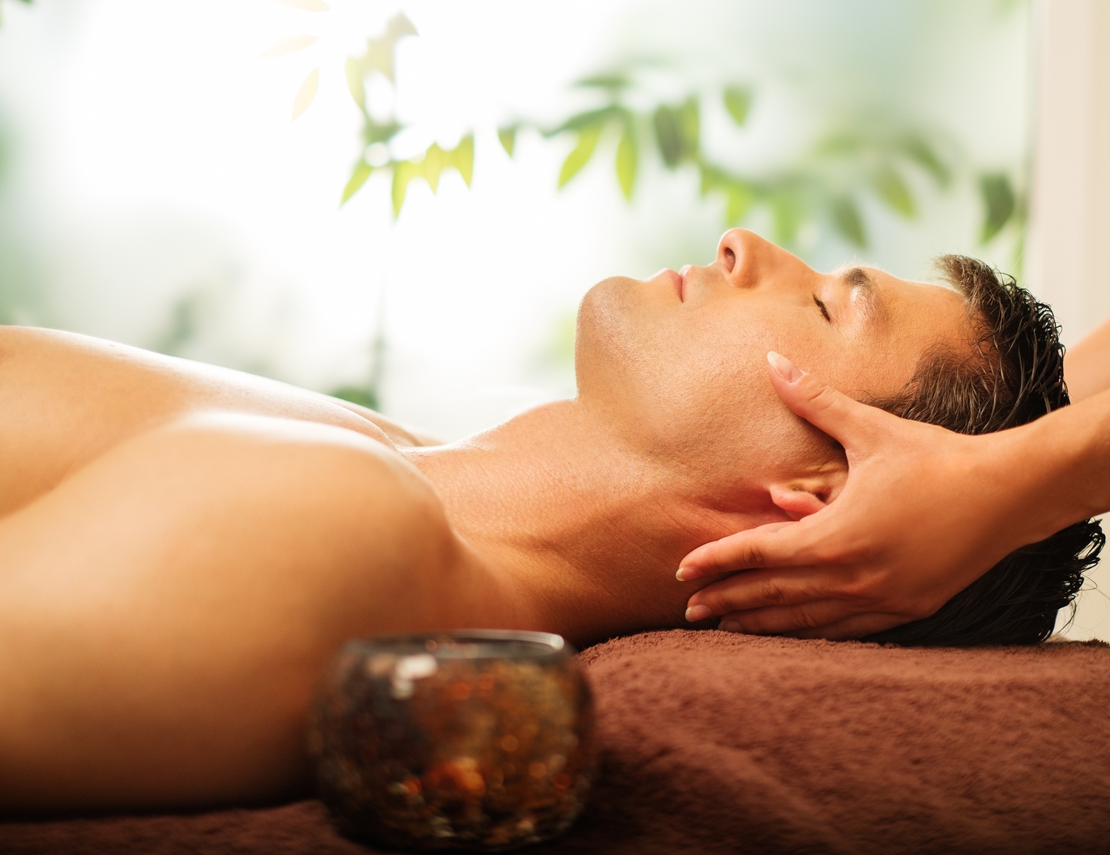 Handsome man having face massage in spa salon